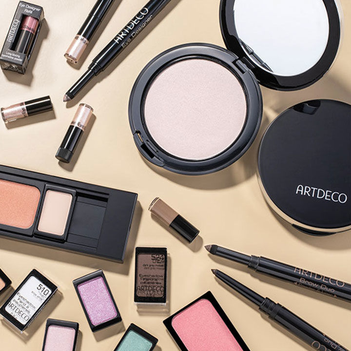 Auf einem hellen Untergrund liegen mehrere Make-Up Produkte von Artdeco