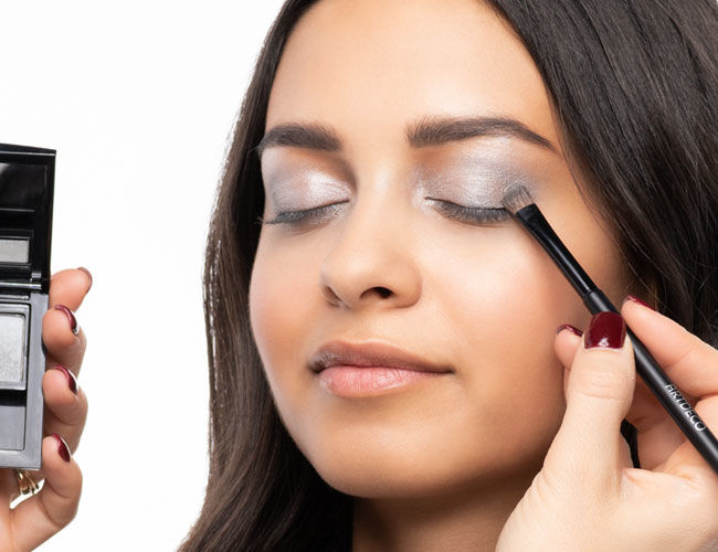 A dark-colored eyeshadow is applied to the lid