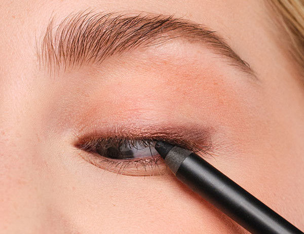 An eyeliner is applied to the upper lash line.